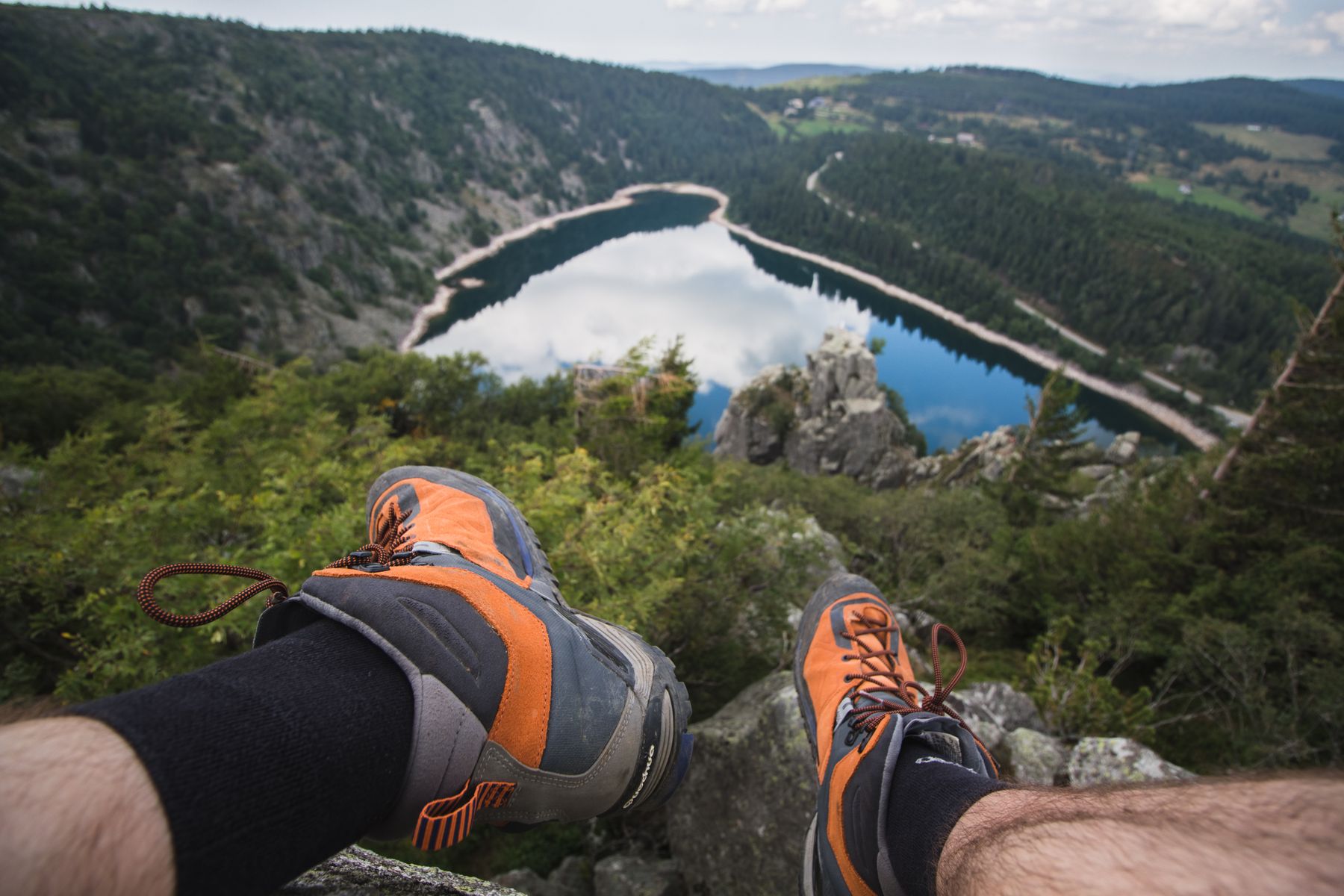 Chaussures de randonnée posées au-dessus d’un lac et de collines boisées